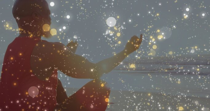 Sitting man facing horizon on shoreline by calm sea, in red sleeveless top with bokeh overlay