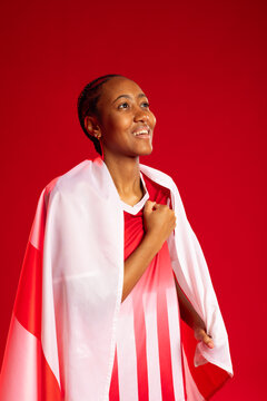 Female standing in studio draping red-and-white flag over striped jersey and wearing stud earrings