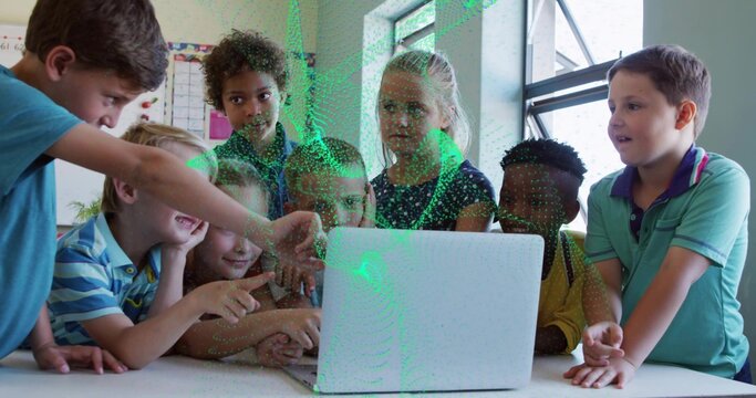 Leaning students pointing at white laptop on classroom table, showing posters and window
