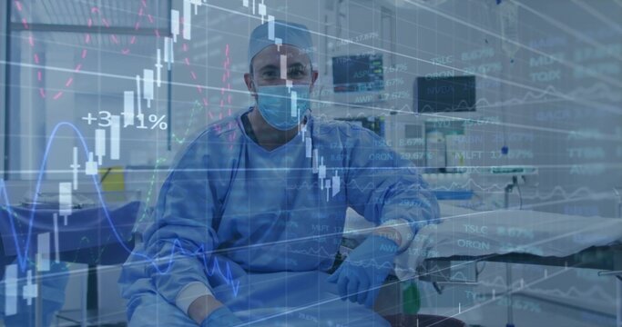 Sitting surgeon wearing blue scrubs, cap, mask, gloves in OR facing empty gurney with market data