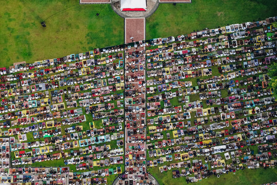 Aerial view of a large crowd of people gathered for prayer on colorful mats on a green field in Klaten, Jawa Tengah, Indonesia.