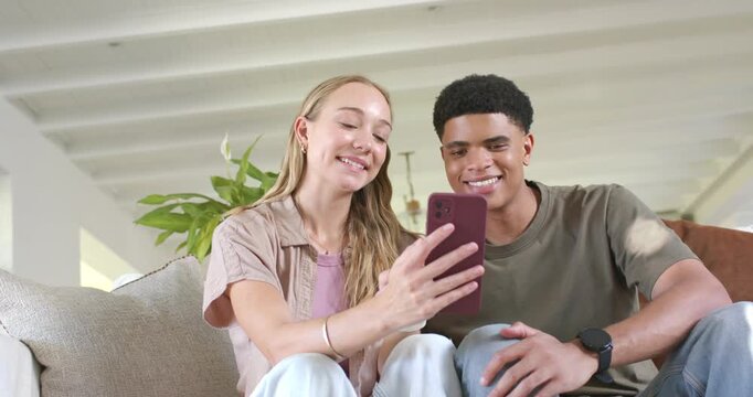 Couple sitting on couch, woman lifting purple phone, tapping and pointing, sharing screen