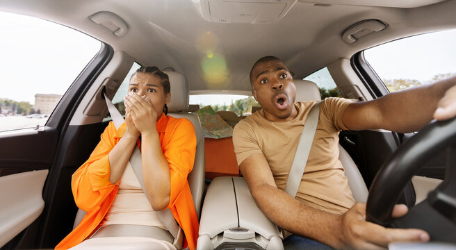 Shocked young African American couple reacting inside a car, expressing fear and surprise, illustrating sudden danger, accident risk and unsafe driving situation