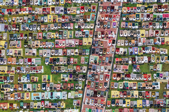 Aerial view of a large crowd of people praying on colorful mats spread across a green lawn during a religious gathering in Klaten, Jawa Tengah, Indonesia.