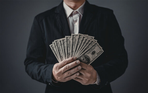 Businessman holding a large stack of us dollar bills in his hands symbolizing wealth and finance