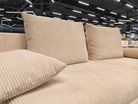 A comfortable beige sofa with three cushions, for sale in a furniture store