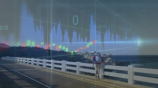 Mid-adult man hiking road, pausing at railing gap, viewing sea, finance charts animating around him