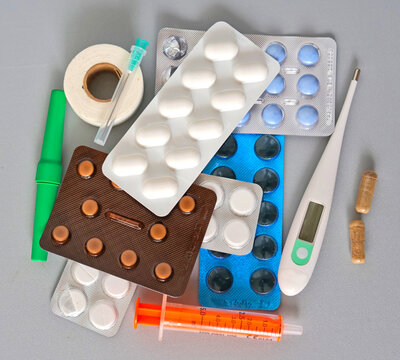 Flat Lay of Assorted Medication Blister Packs Thermometer Syringe and Medical Supplies on Grey Background | Everything in Your Home Medicine Cabinet in One Place