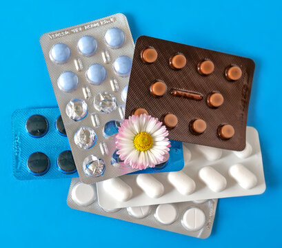 Multiple Medication Blister Packs with Different Tablets and a Daisy Flower on Blue Background | Between Nature and Medicine, Finding Your Own Path to Healing