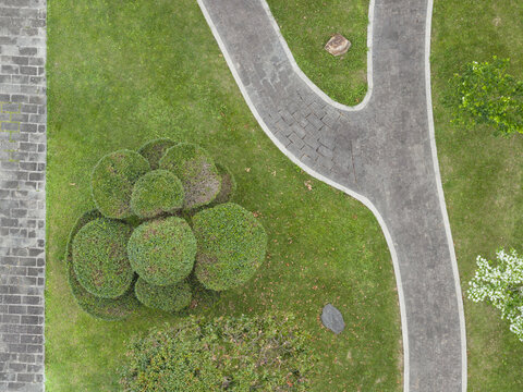 Aerial view of a manicured garden with a winding stone path, lush green lawn, and decorative topiary bushes in Taiwan.