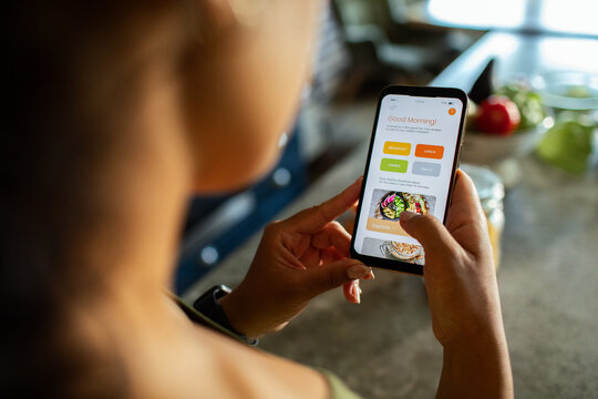 Woman using meal planning app in home kitchen