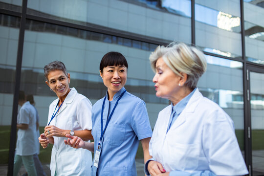 Three healthcare professionals talking outside a hospital
