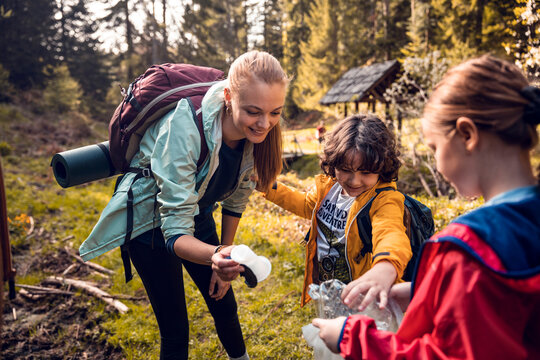 Mother and kids picking up litter while hiking in forest