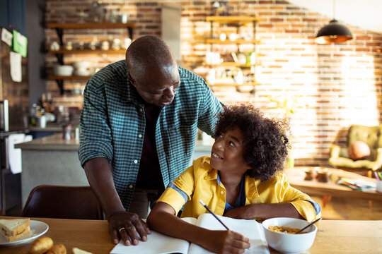 Parent helping child with homework at kitchen table