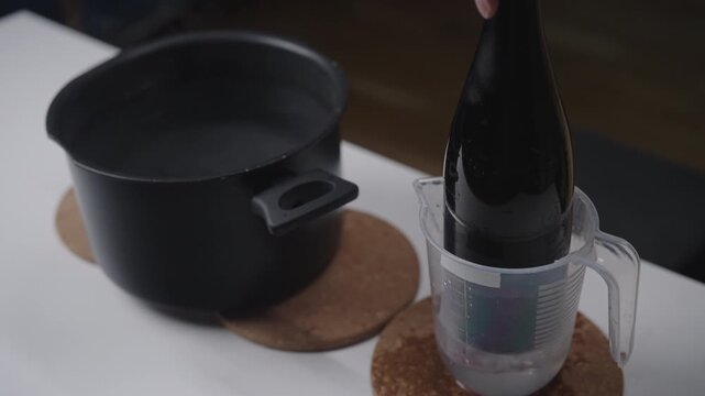 Glass bottle cutting method demonstrating thermal shock with hot and cold water, do it yourself crafting technique for making drinking glass from trash, close-up, slow motion.