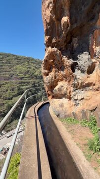 Traditional irrigation canal known as a levada flowing through a narrow hand-carved rock tunnel on a hiking route in Madeira Portugal.
