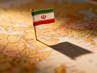 Naklejka premium Iranian flag pin on vintage world map, national flag of Iran marking location on antique atlas, geopolitical concept and travel destination isolated on White Background