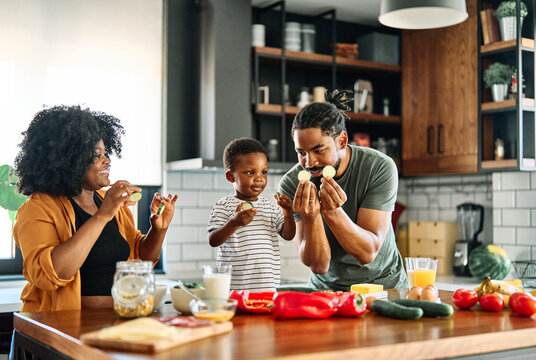 Portrait of mother, father and son preparing a mea and having funl in the kitchen at home