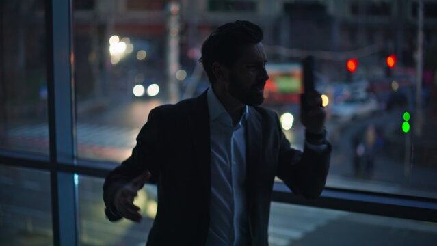Emotional boss conflicting cellphone yelling gesturing in dark office closeup.