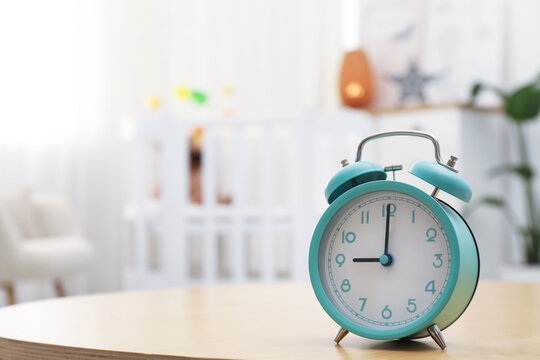 Alarm clock on table in nursery, closeup. Space for text