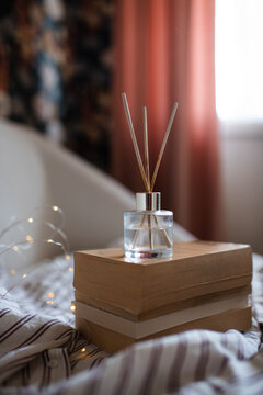 Aroma liquid glass bottle diffuser with wooden sticks on stack of old paper books in living room. Aromatherapy.