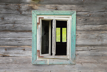 Obraz premium Weathered wooden facade with a window, broken glass pane. Abandoned house.