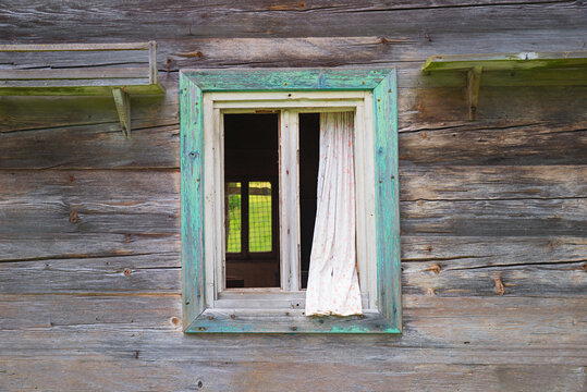 Weathered wooden facade with a window, without glass pane. Abandoned house.