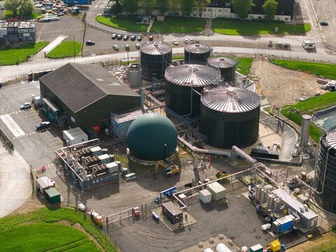 Aerial view of grain storage silos and a water treatment plant with industrial tanks and a green gas holder in Hemswell Cliff, England, United Kingdom.