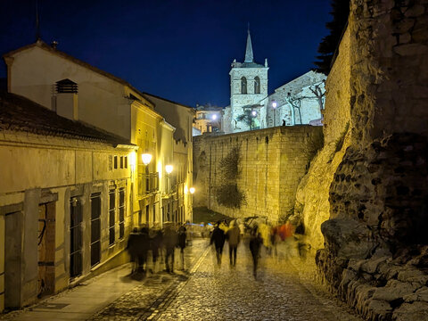 Calle Herreros at night, atmospheric view of a historic cobbled street with blurred pedestrians and the illuminated Church of San Cipriano rising in the background, Zamora, Castile and Le&oacute;n, Spain.