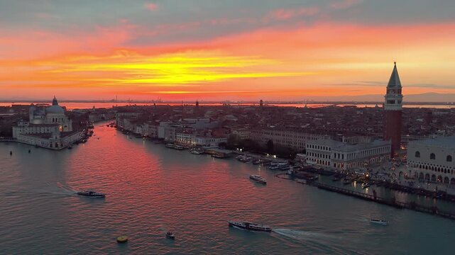 Venice aerial sunset over lagoon, boats gliding past basilica santa maria della salute, pastel sky casting. Italy