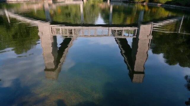Bridge reflection on calm water surface with trees in background