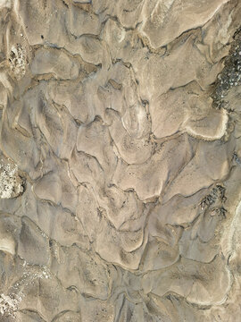 Close up view of sunlit sandy soil patterns showing sediment textures in a natural outdoor space during daylight hours