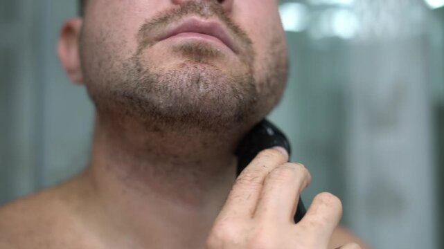 Man shaving neck with electric trimmer close up grooming routine