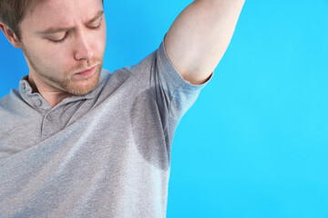 Naklejka premium Man with sweaty armpits on light blue background, closeup. Space for text