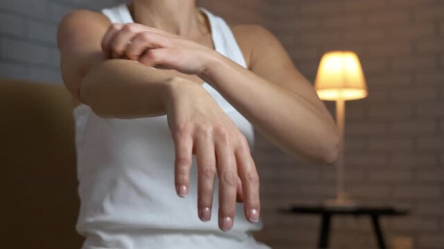 Woman with itchy skin scratching arm. Uncomfortable young woman suffering from itchy skin, scratching her irritated arm due to an allergic reaction, insect bite, or dermatitis, causing discomfort
