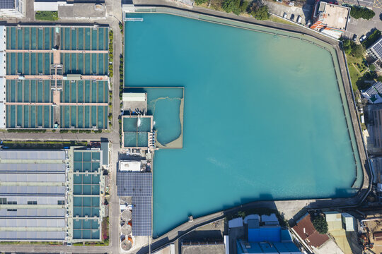 Aerial view of a water treatment plant featuring large turquoise sedimentation tanks and rectangular filtration basins under bright sunlight in Taiwan.