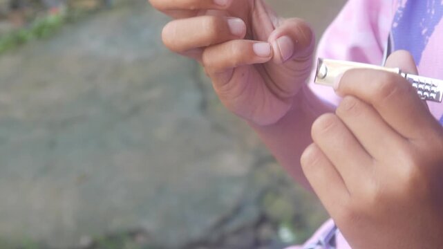 a man is cutting his fingernails using a metal nail clipper