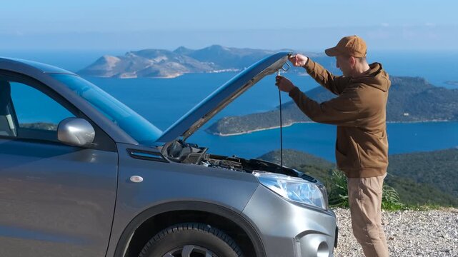 Frustrated man opening the hood of a broken down car on a road trip. Worried driver experiencing a car breakdown during a scenic journey, opening the hood to inspect the engine and figure out