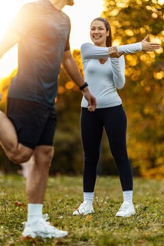 Couple exercises in the park during sunset while warming up and stretching before running