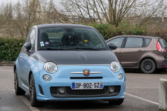 Nancy, France - April 2nd 2022 : View on a grey and blue Abarth 595 Turismo parked on a parking lot with a car and vegetation in the background.