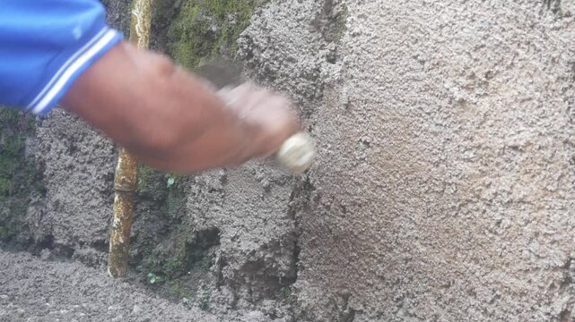 A construction worker is plastering a wall using a cement trowel on a house wall.