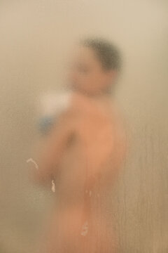 Young woman naked in a shower behind glass