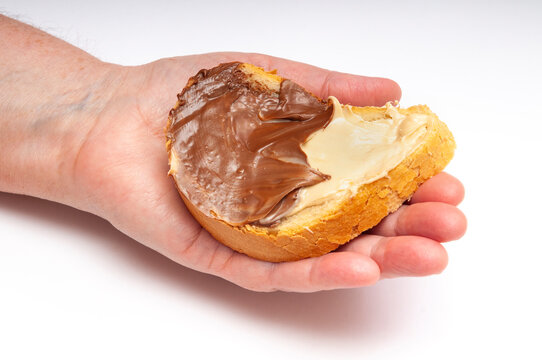 Hand holding bread slice with cream spread