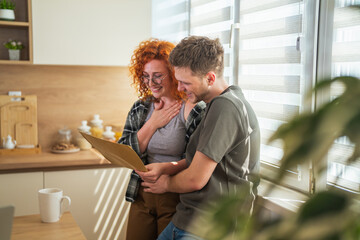 Fototapeta premium Happy couple receiving exciting news at home kitchen