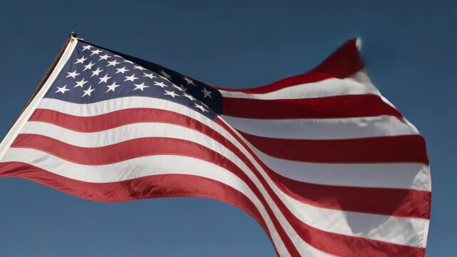 American Flag Waving in the Wind Against Clear Blue Sky