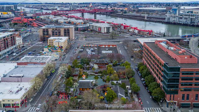 Aerial view of Lan Su Chinese Garden featuring traditional pavilions and a pond overlooking the city skyline and Willamette River Portland, Oregon, United States.