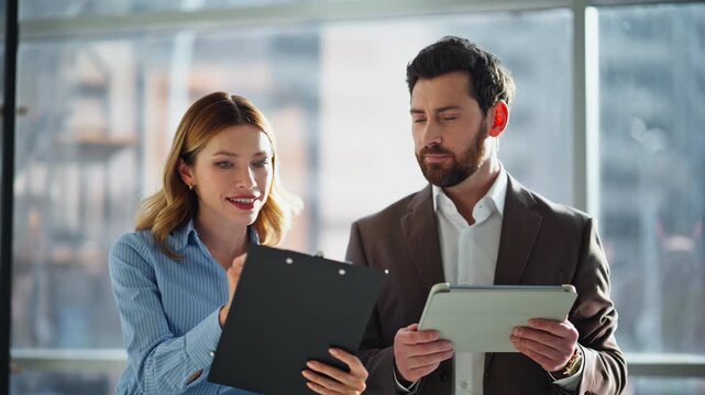 Partners agree deal details looking papers browsing tablet at office closeup.