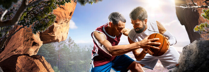 Basketball. Two basketball players practice on a basketball court in the wilderness. A beautiful landscape is in the background. © 103tnn