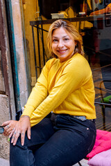 Fototapeta premium Happy woman in yellow sweater smiling outdoors in city