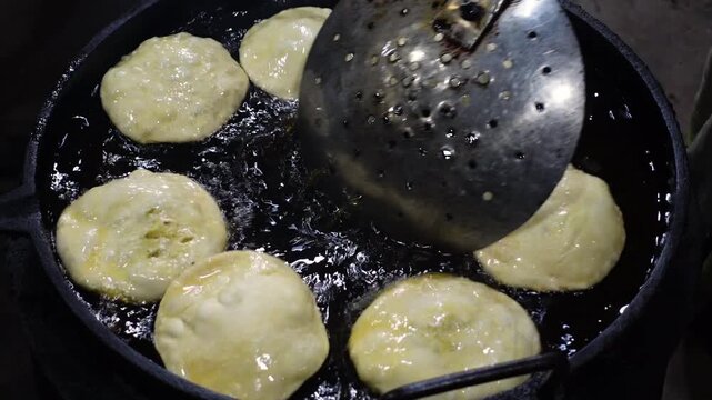 Crispy puris are being fried in hot oil for eating. Puri, potato and flour mixing snack recipe.